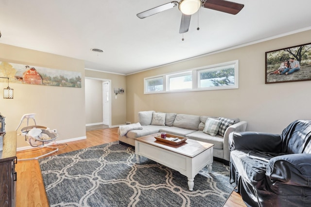 living room with wood-type flooring, ornamental molding, and ceiling fan