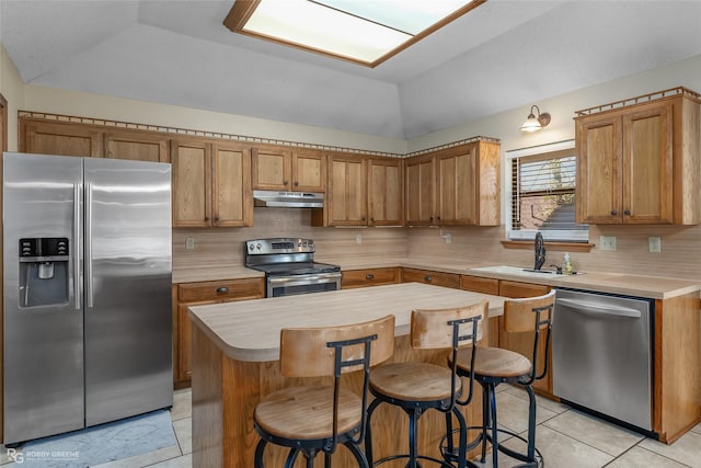 kitchen featuring lofted ceiling, sink, appliances with stainless steel finishes, a kitchen island, and decorative backsplash