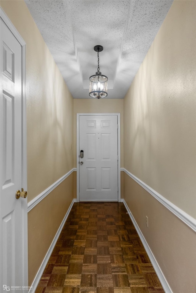 doorway to outside featuring a chandelier, dark parquet floors, and a textured ceiling