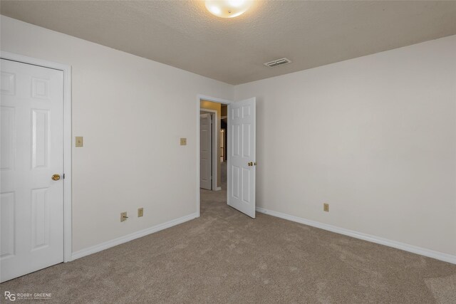 carpeted empty room featuring a textured ceiling