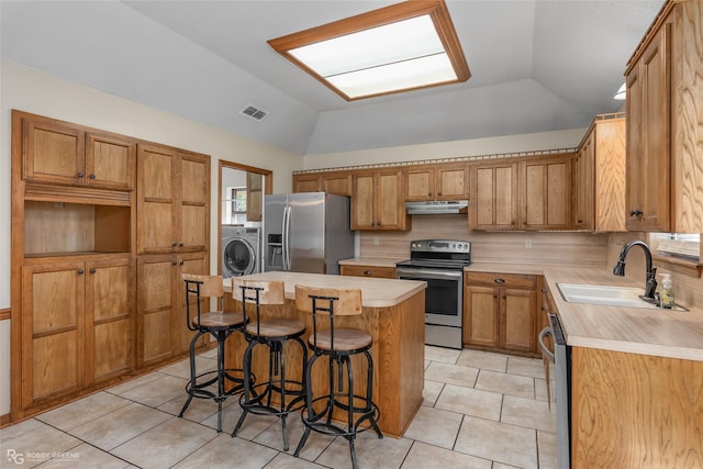 kitchen with appliances with stainless steel finishes, a breakfast bar, lofted ceiling, sink, and a center island