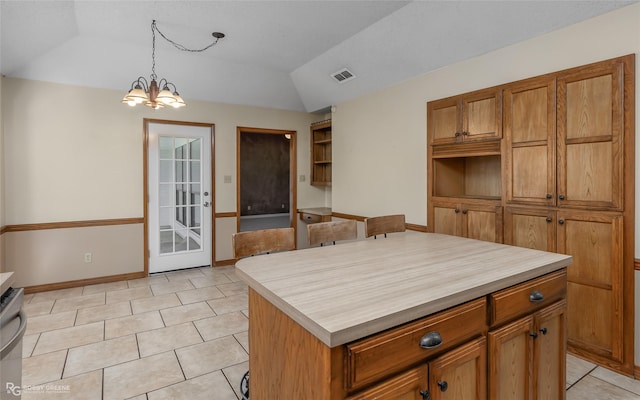 kitchen with pendant lighting, an inviting chandelier, a kitchen island, light tile patterned flooring, and vaulted ceiling