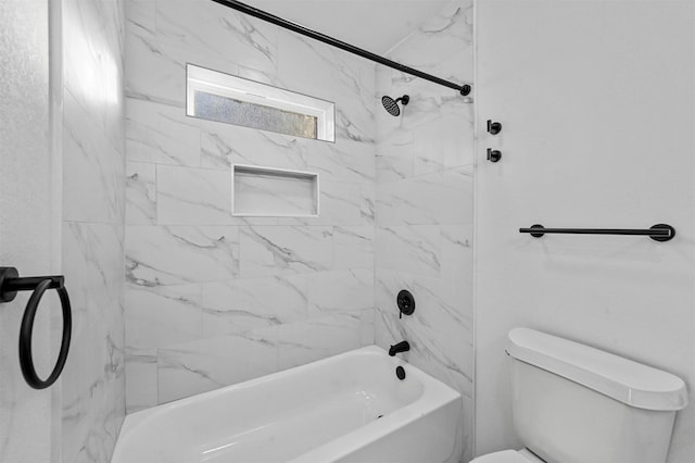 bathroom featuring tiled shower / bath combo and toilet