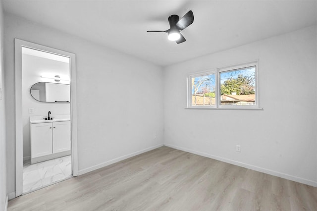 empty room featuring light wood-type flooring, ceiling fan, and sink