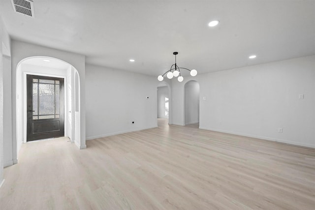 empty room featuring light wood-type flooring and a notable chandelier