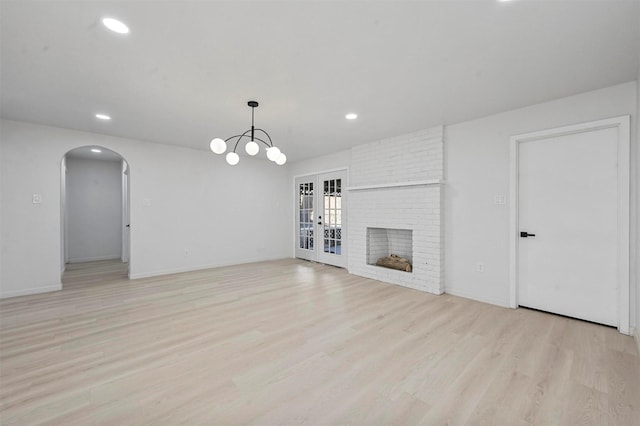 unfurnished living room featuring a fireplace, light hardwood / wood-style flooring, and french doors