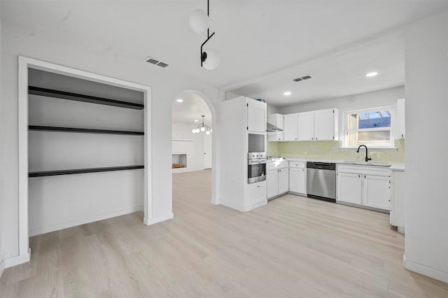 kitchen with stainless steel appliances, white cabinetry, tasteful backsplash, and light hardwood / wood-style flooring