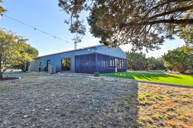 rear view of property with a sunroom, central air condition unit, and a yard