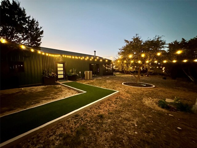 yard at dusk featuring central AC