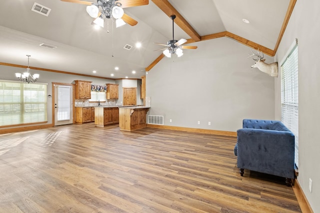 kitchen featuring high vaulted ceiling, wood-type flooring, ornamental molding, and kitchen peninsula