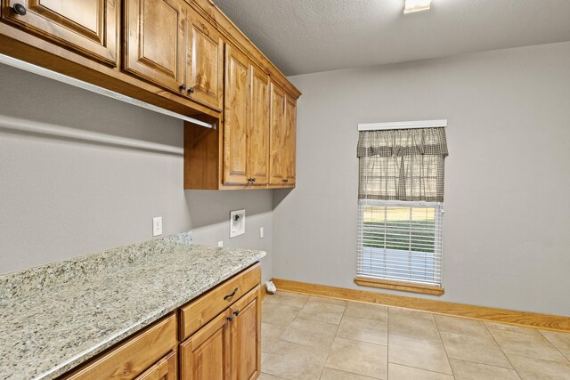 interior space with light stone counters, a textured ceiling, and light tile patterned floors