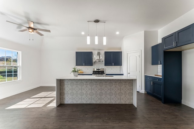 kitchen with pendant lighting, wall chimney range hood, blue cabinetry, and vaulted ceiling