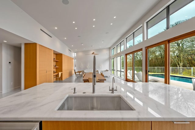 kitchen with stainless steel dishwasher, light stone countertops, and sink