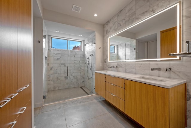 bathroom with vanity, a shower with shower door, and tile walls