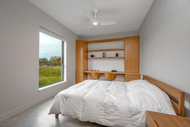 bedroom with built in desk, concrete floors, and ceiling fan