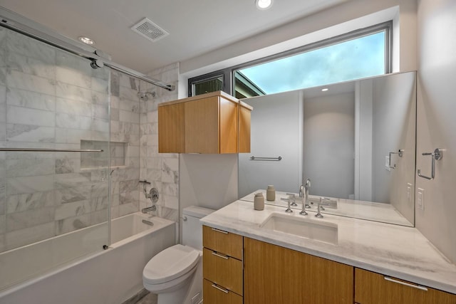 full bathroom featuring vanity, tiled shower / bath combo, and toilet