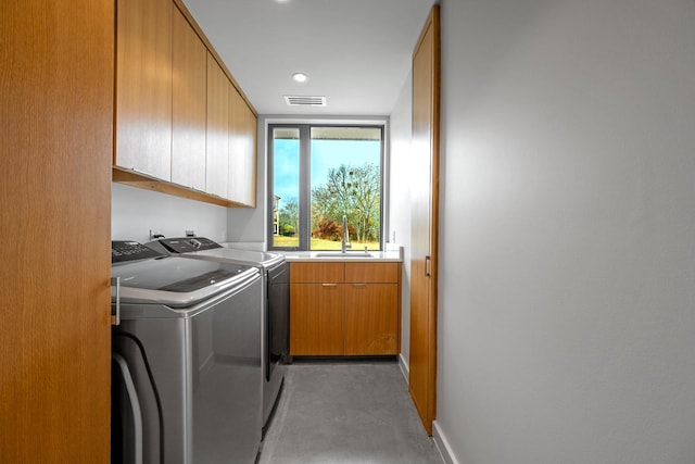 washroom with cabinets, washer and clothes dryer, and sink