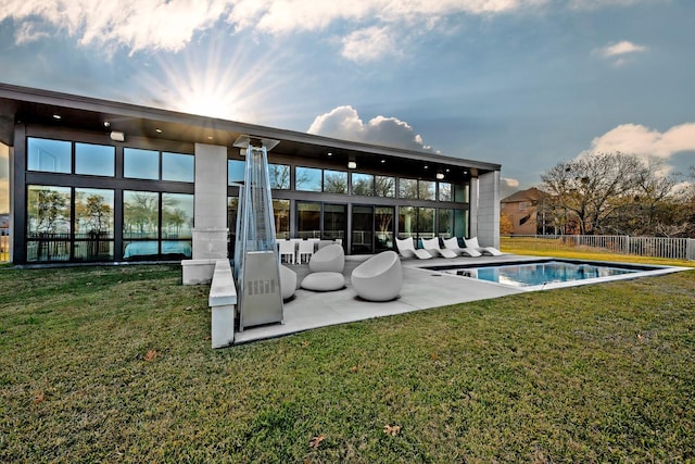 back of house with a fenced in pool, a patio area, and a lawn