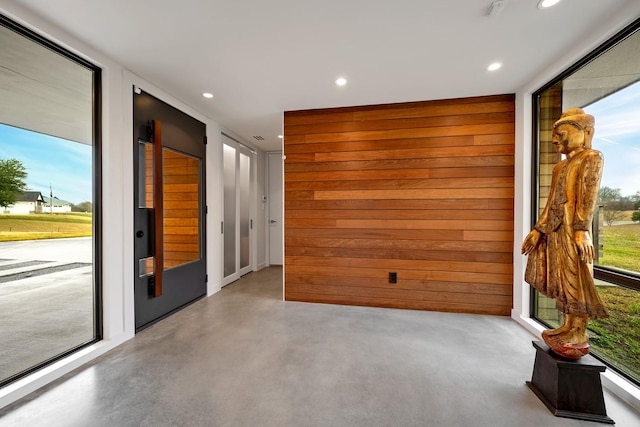 unfurnished room featuring plenty of natural light and wooden walls