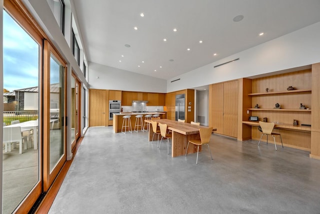 dining area featuring a towering ceiling and built in desk