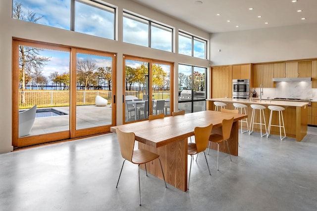 dining room featuring a healthy amount of sunlight, a towering ceiling, and sink