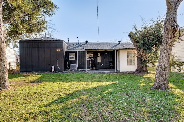 rear view of house featuring central AC unit and a yard