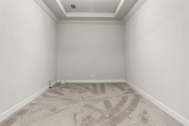 unfurnished room featuring a tray ceiling and light colored carpet