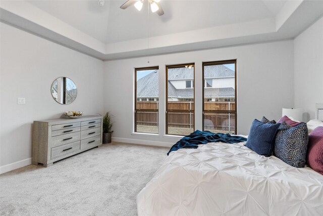 carpeted bedroom featuring ceiling fan and a raised ceiling