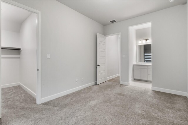 unfurnished bedroom featuring light carpet and ensuite bath