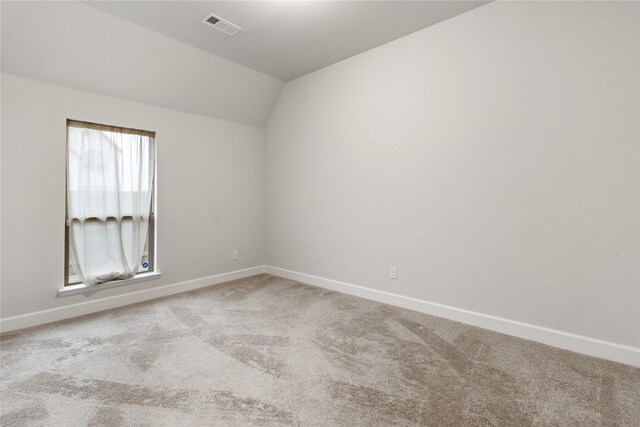 carpeted spare room with vaulted ceiling