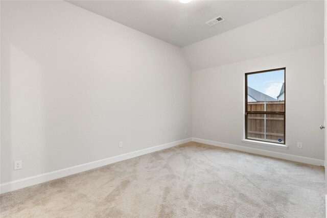 carpeted spare room with vaulted ceiling