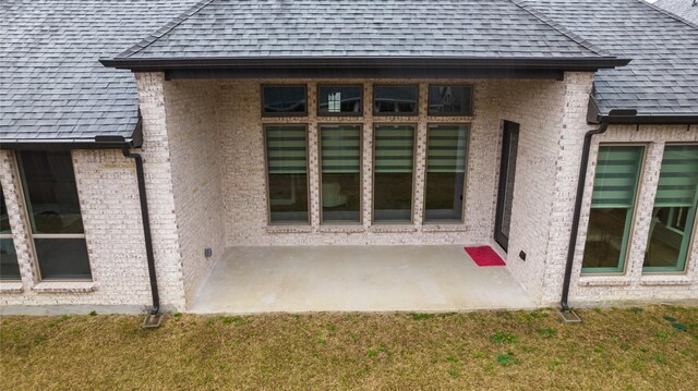 view of exterior entry with a yard and a patio