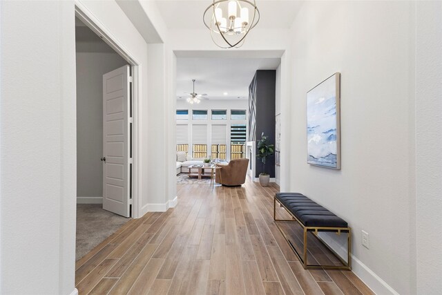 hallway with hardwood / wood-style flooring and a notable chandelier