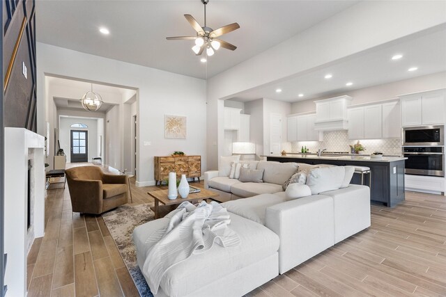 living room featuring ceiling fan with notable chandelier and light hardwood / wood-style floors