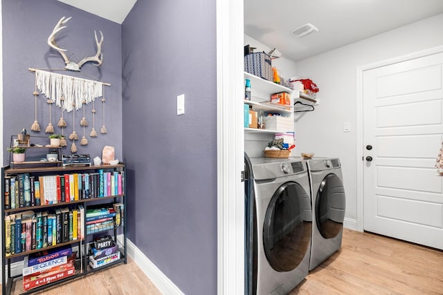 laundry area featuring washing machine and dryer and light hardwood / wood-style flooring