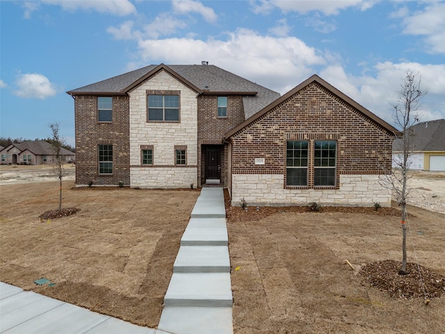 traditional-style house with stone siding, a shingled roof, and brick siding