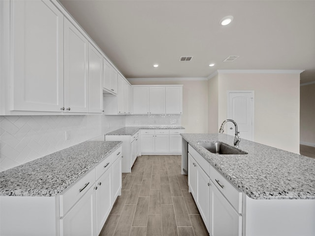 kitchen with backsplash, a sink, visible vents, and light stone countertops