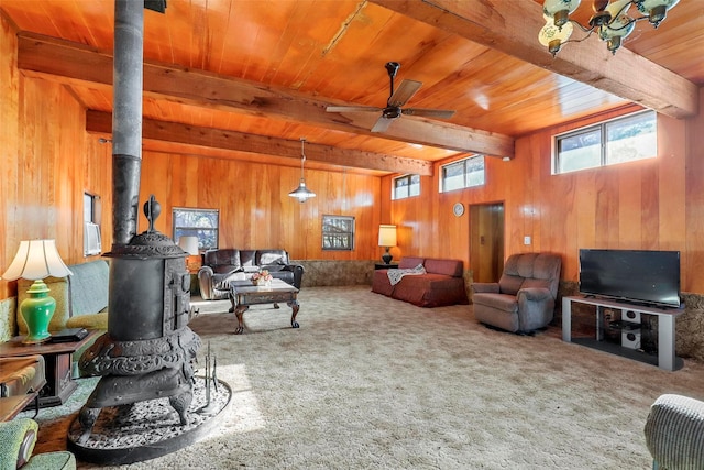 living room with beamed ceiling, carpet, a wood stove, and wooden walls