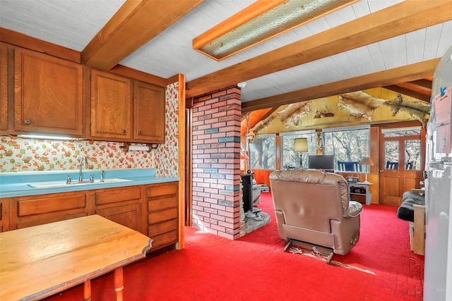 kitchen featuring sink, carpet floors, and vaulted ceiling with beams