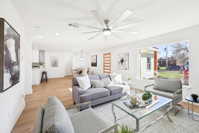 living room with ceiling fan and light hardwood / wood-style flooring