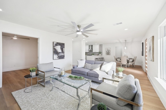 living room with ceiling fan and light hardwood / wood-style flooring