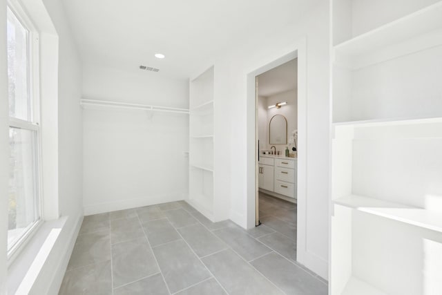 spacious closet featuring light tile patterned floors and sink