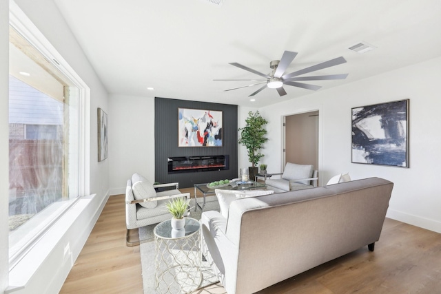 living room with light wood-type flooring, plenty of natural light, and ceiling fan