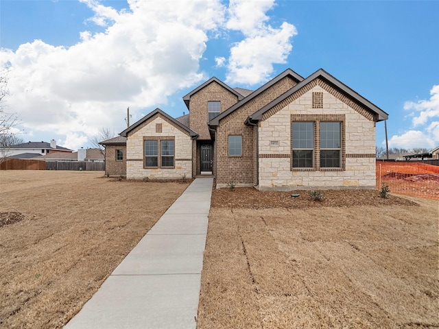 view of front of property featuring stone siding, fence, and a front yard