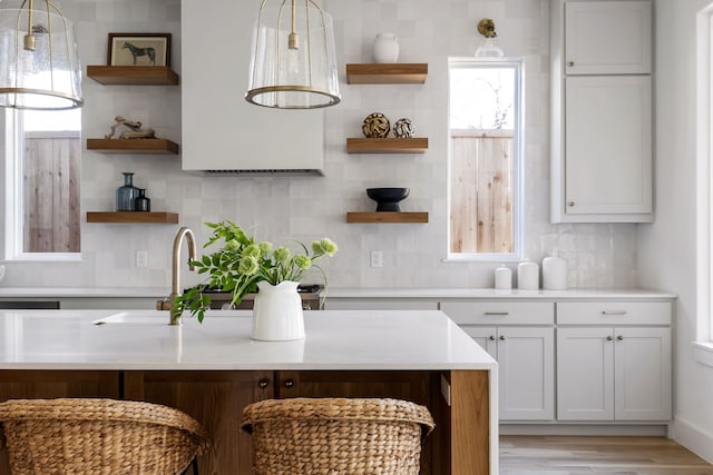 kitchen with backsplash, sink, pendant lighting, light hardwood / wood-style flooring, and white cabinets