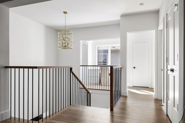 hall with hardwood / wood-style flooring and an inviting chandelier