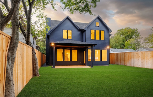 back house at dusk with a patio area and a yard