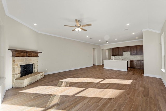 unfurnished living room with a stone fireplace, ceiling fan, dark hardwood / wood-style floors, and ornamental molding