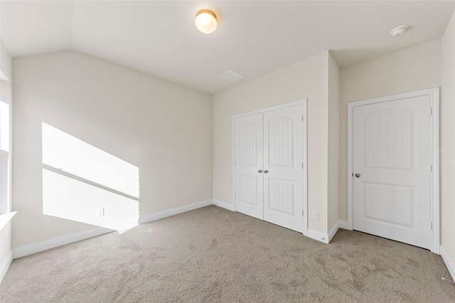 unfurnished bedroom with light colored carpet, lofted ceiling, and a closet