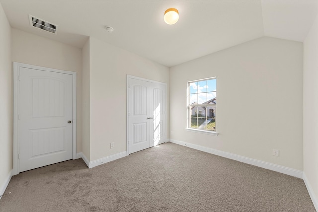 unfurnished bedroom featuring light carpet and lofted ceiling